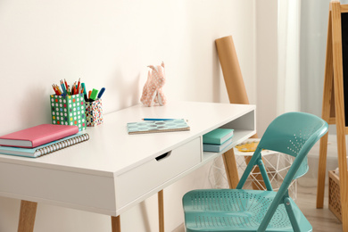 Table with chair near white wall in child room