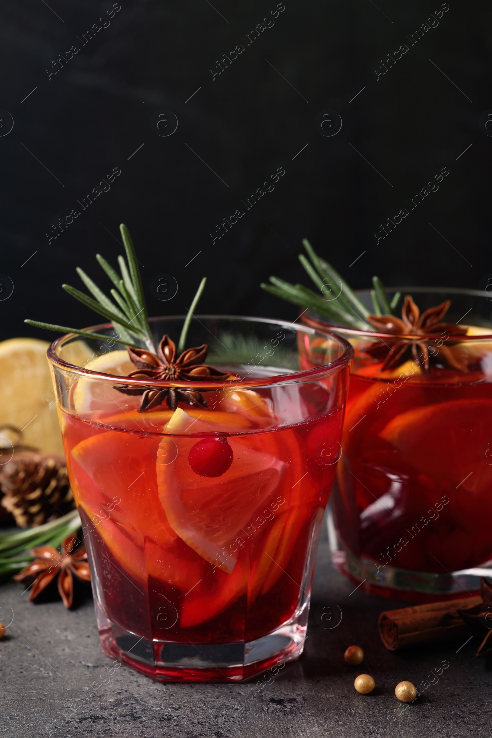 Photo of Delicious punch drink with cranberries, orange and spices on grey table