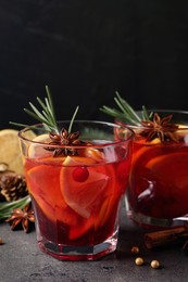 Delicious punch drink with cranberries, orange and spices on grey table