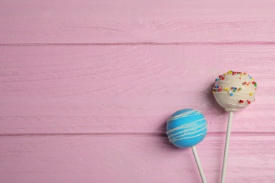 Bright delicious cake pops on wooden table, flat lay. Space for text