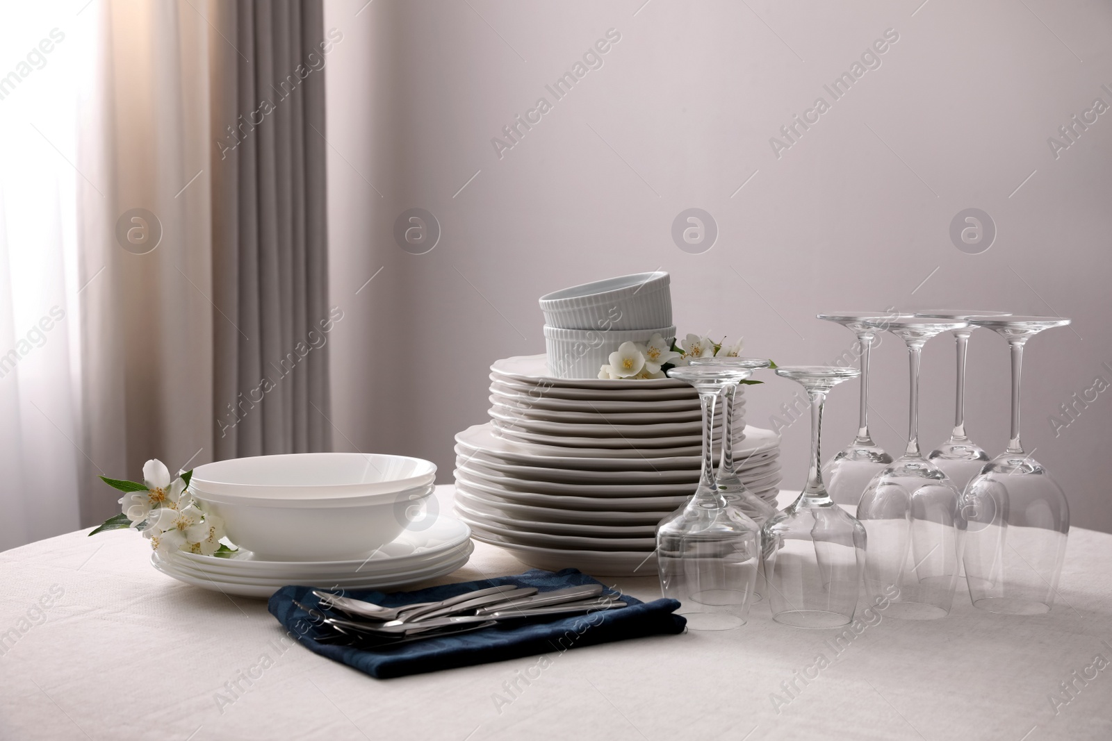 Photo of Set of clean dishware, cutlery and wine glasses on table indoors