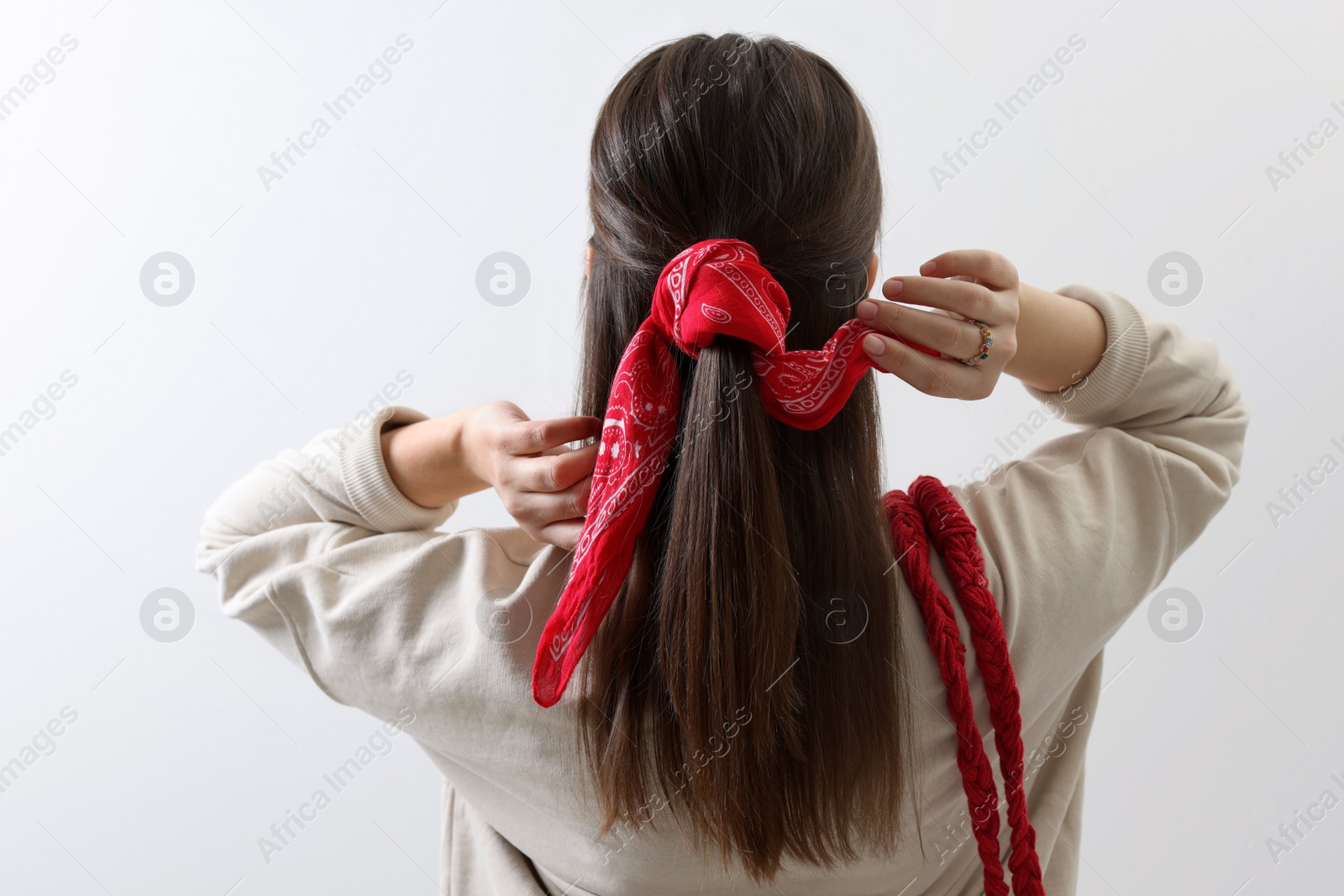 Photo of Young woman with stylish red bandana on light background, back view