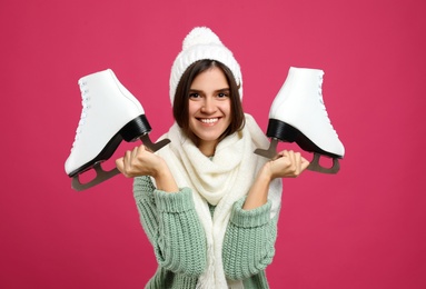 Happy woman with ice skates on pink background