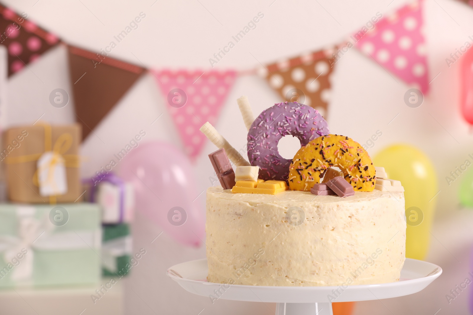 Photo of White stand with delicious cake decorated with sweets against blurred background, space for text