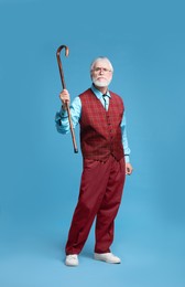 Photo of Angry senior man with walking cane on light blue background