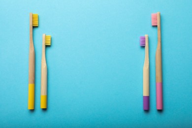 Photo of Bamboo toothbrushes and space for text on turquoise background, flat lay. Eco friendly products