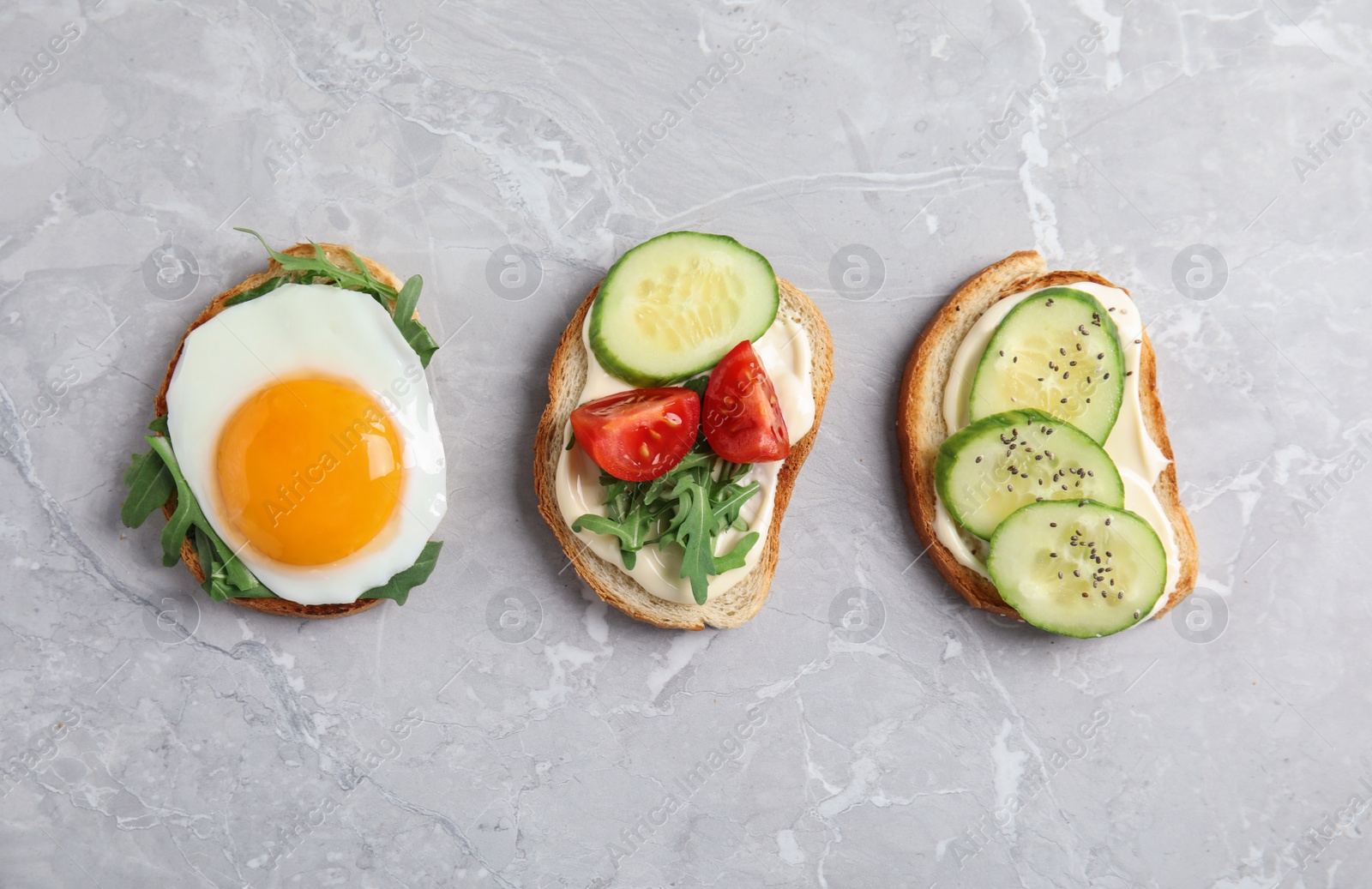 Photo of Slices of bread with different toppings on grey marble table, flat lay