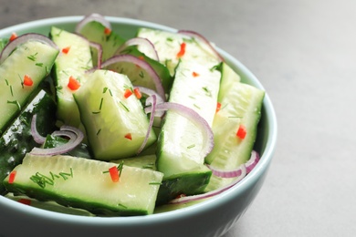 Photo of Delicious cucumber salad with onion in bowl on grey background, closeup