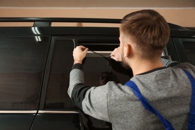 Photo of Skilled worker tinting car window in shop