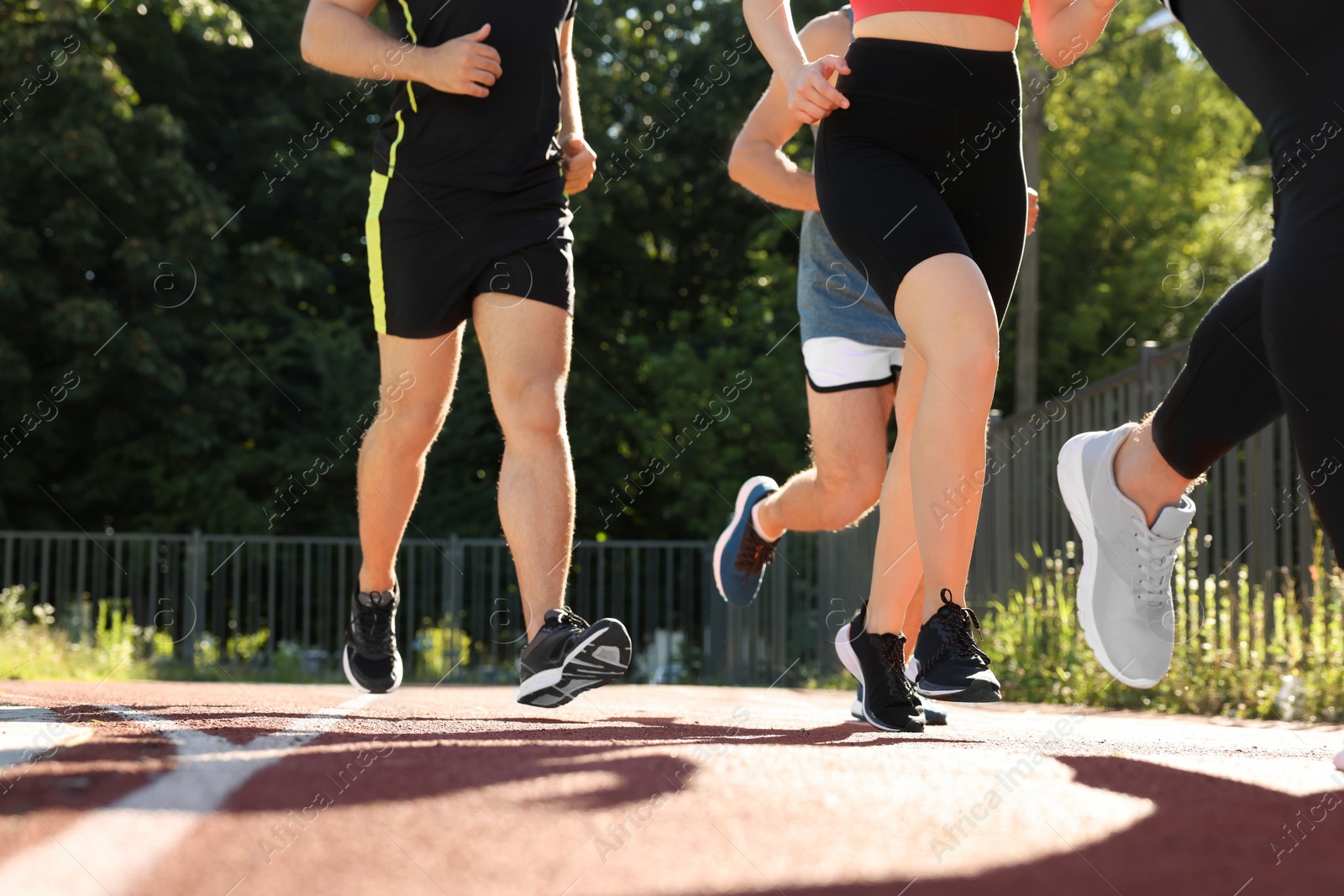 Photo of Group of people running at stadium on sunny day, closeup