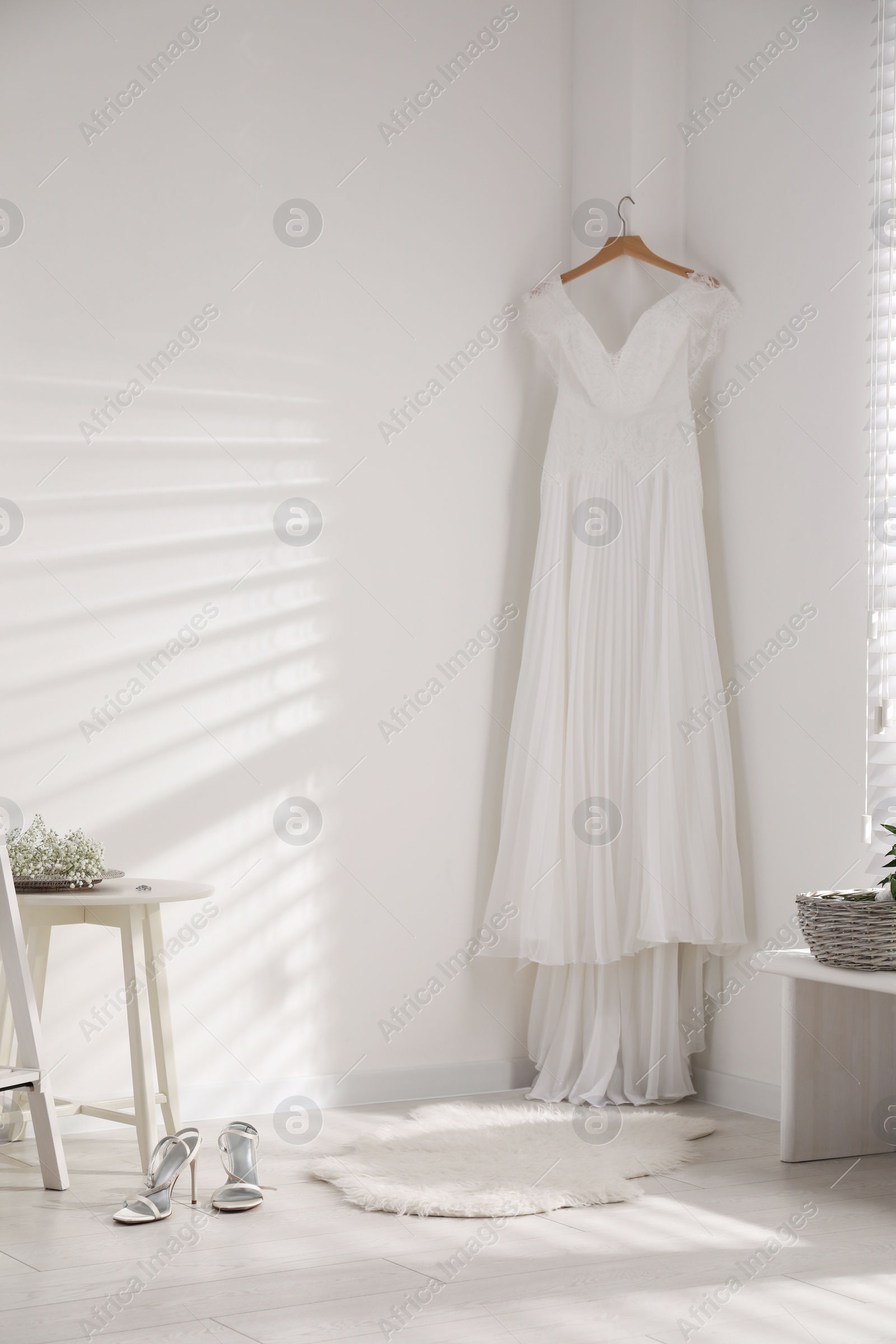 Photo of Beautiful wedding dress hanging on white wall in room