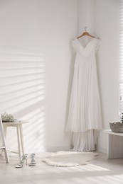 Photo of Beautiful wedding dress hanging on white wall in room