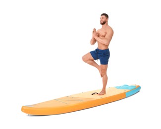 Photo of Happy man practicing yoga on orange SUP board against white background