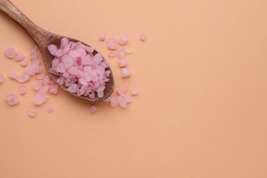 Photo of Spoon with pink sea salt on beige background, top view. Space for text