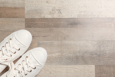 Photo of Stylish sneakers on wooden floor, flat lay. Space for text