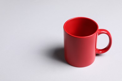Photo of One red ceramic mug on light background, space for text