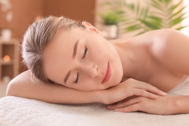 Photo of Young woman lying on massage table in spa salon