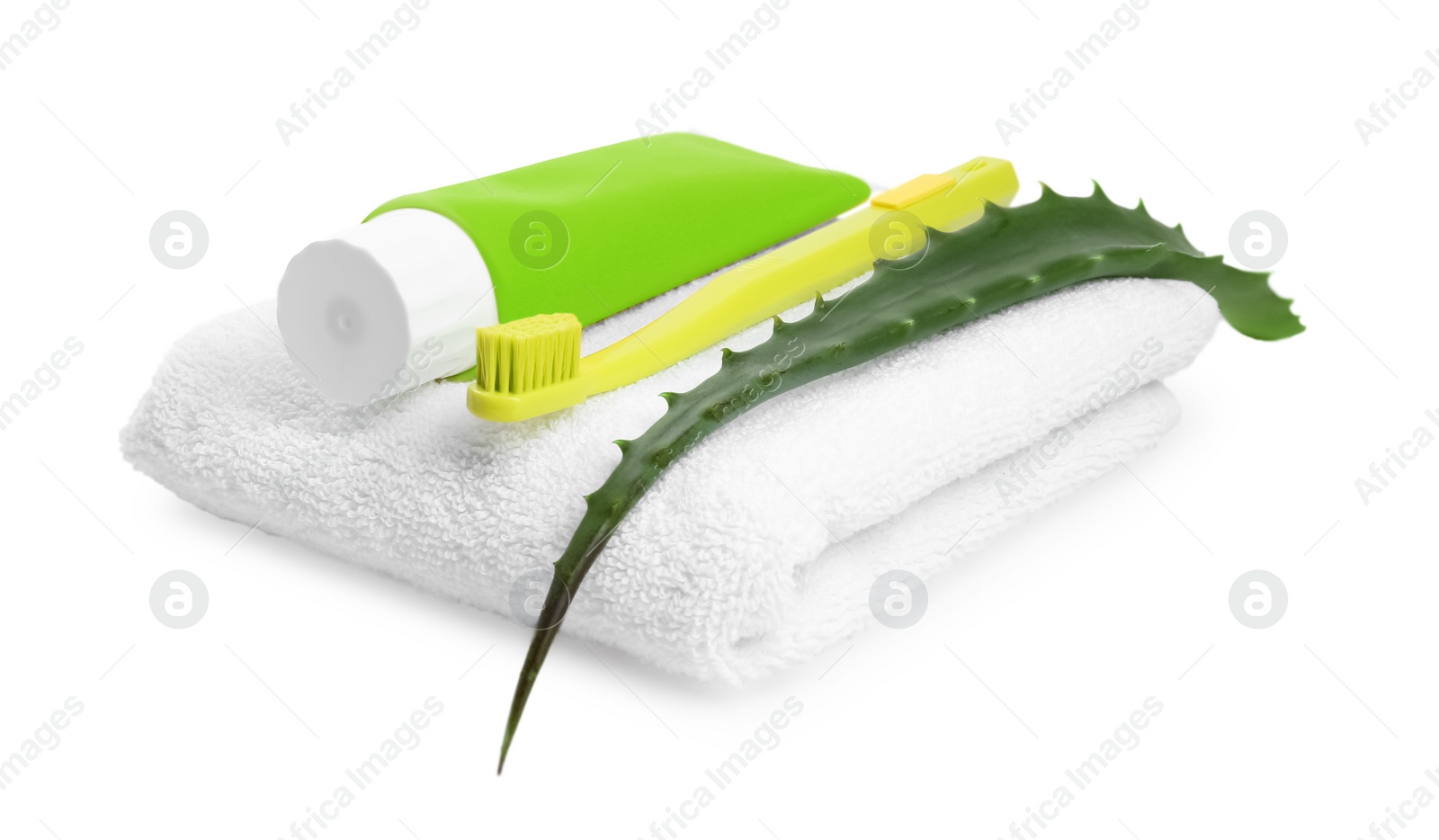 Photo of Tube of toothpaste, brush, aloe vera leaf and towel on white background