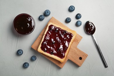 Photo of Toast with blueberry jam served on grey table, flat lay