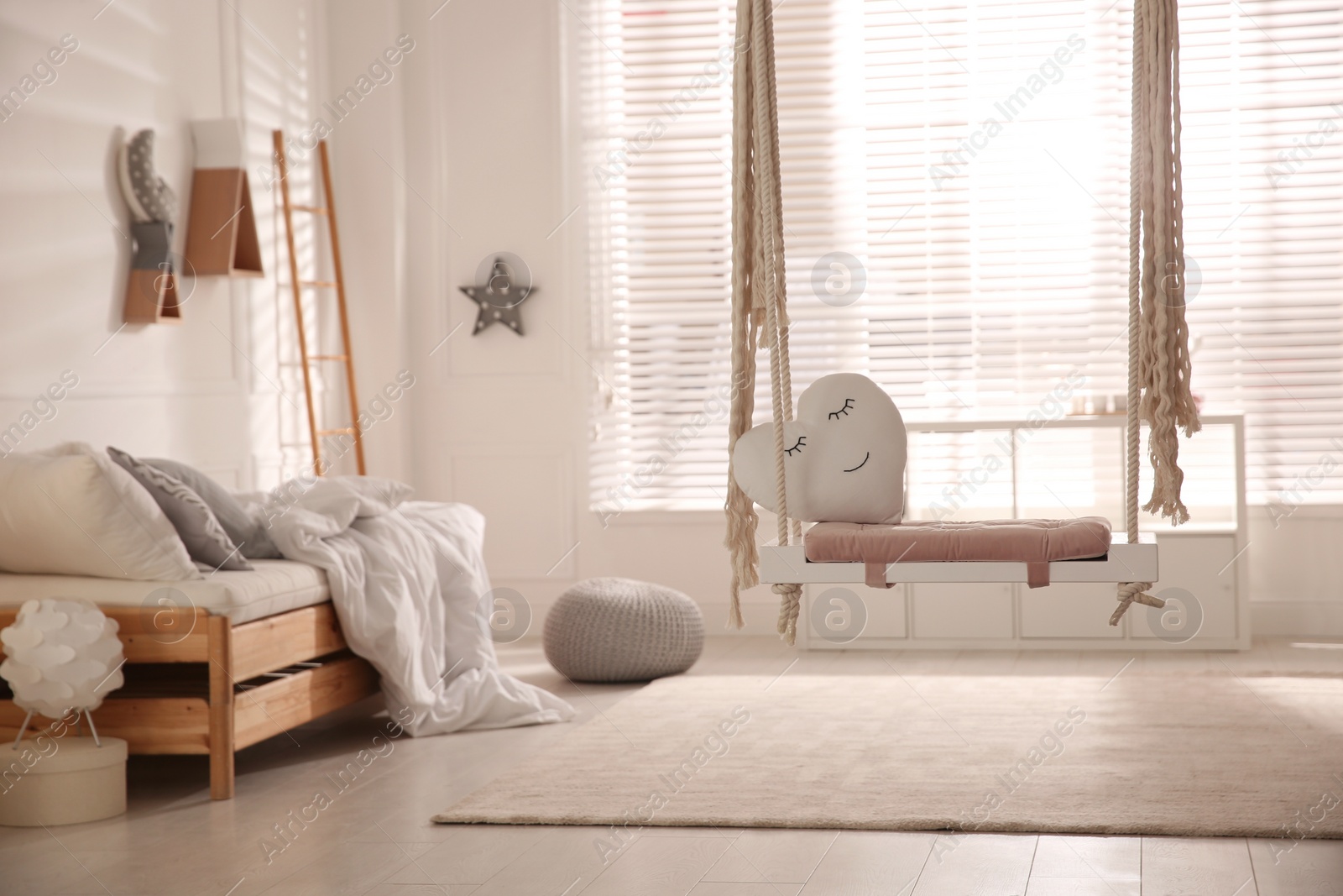 Photo of Beautiful swing with toy heart in bedroom. Stylish interior design