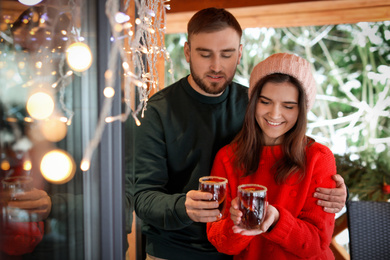Photo of Lovely couple with tasty mulled wine in cafe. Winter vacation