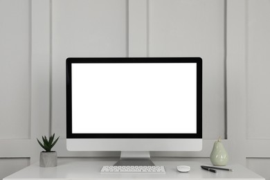 Photo of Modern computer, decor and office supplies on white wooden table near molding wall