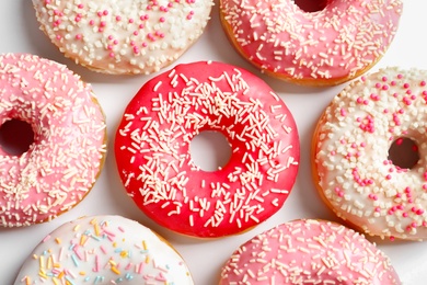 Photo of Delicious glazed doughnuts with sprinkles on light background, top view