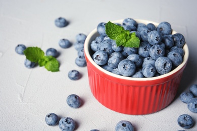 Crockery with juicy and fresh blueberries on color table