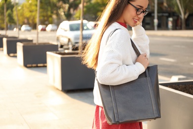 Young woman with stylish shopper bag outdoors. Space for text