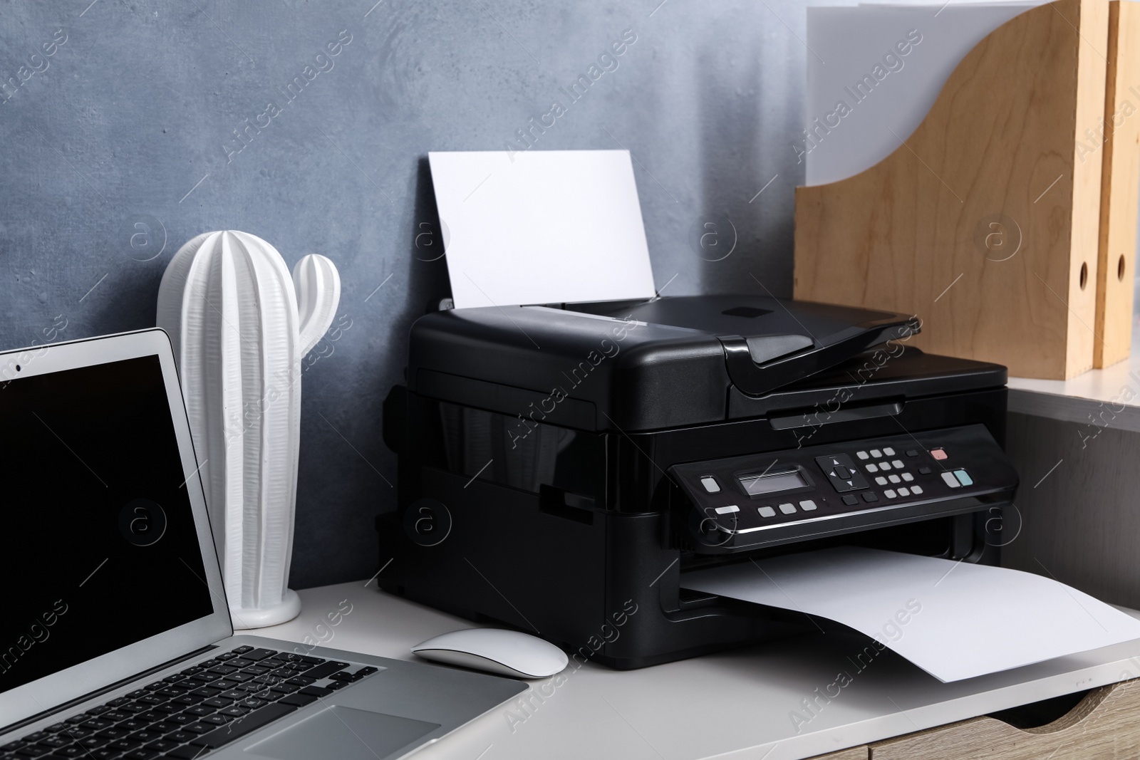 Photo of Modern printer, laptop and decor element on white table