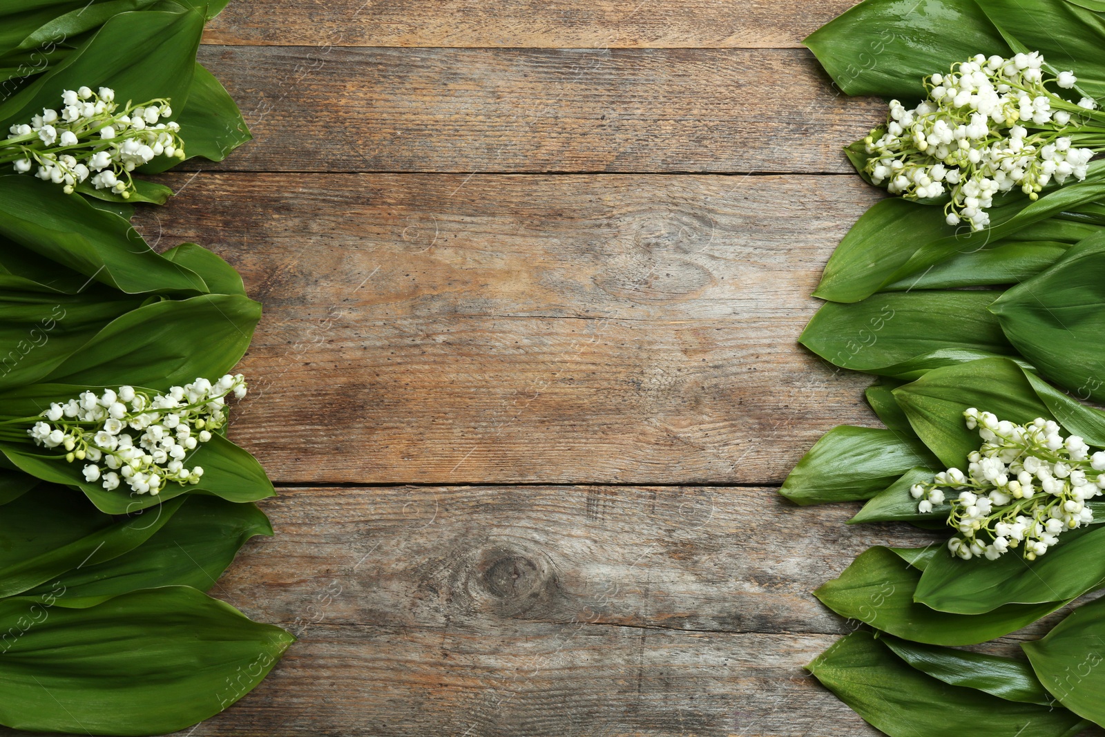 Photo of Frame made with lily of the valley flowers on wooden background, flat lay. Space for text