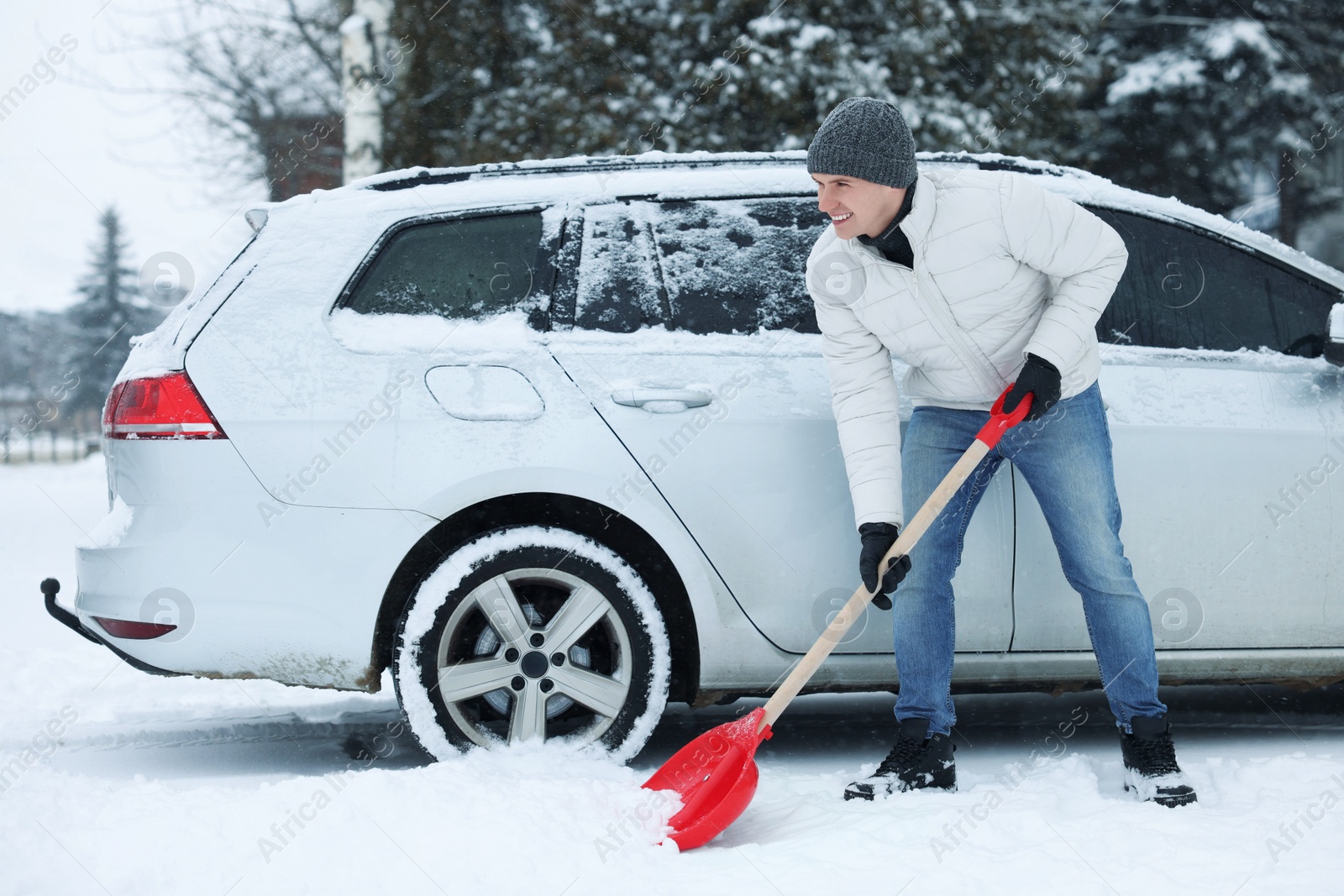 Photo of Man removing snow with shovel near car outdoors