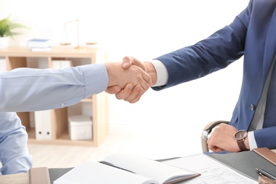 Lawyer handshaking with client over table in office, closeup