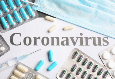 Flat lay composition with word CORONAVIRUS and medicine on table