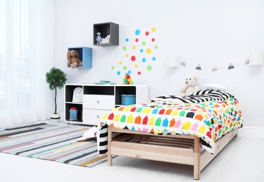 Modern child room interior with comfortable bed and striped carpet