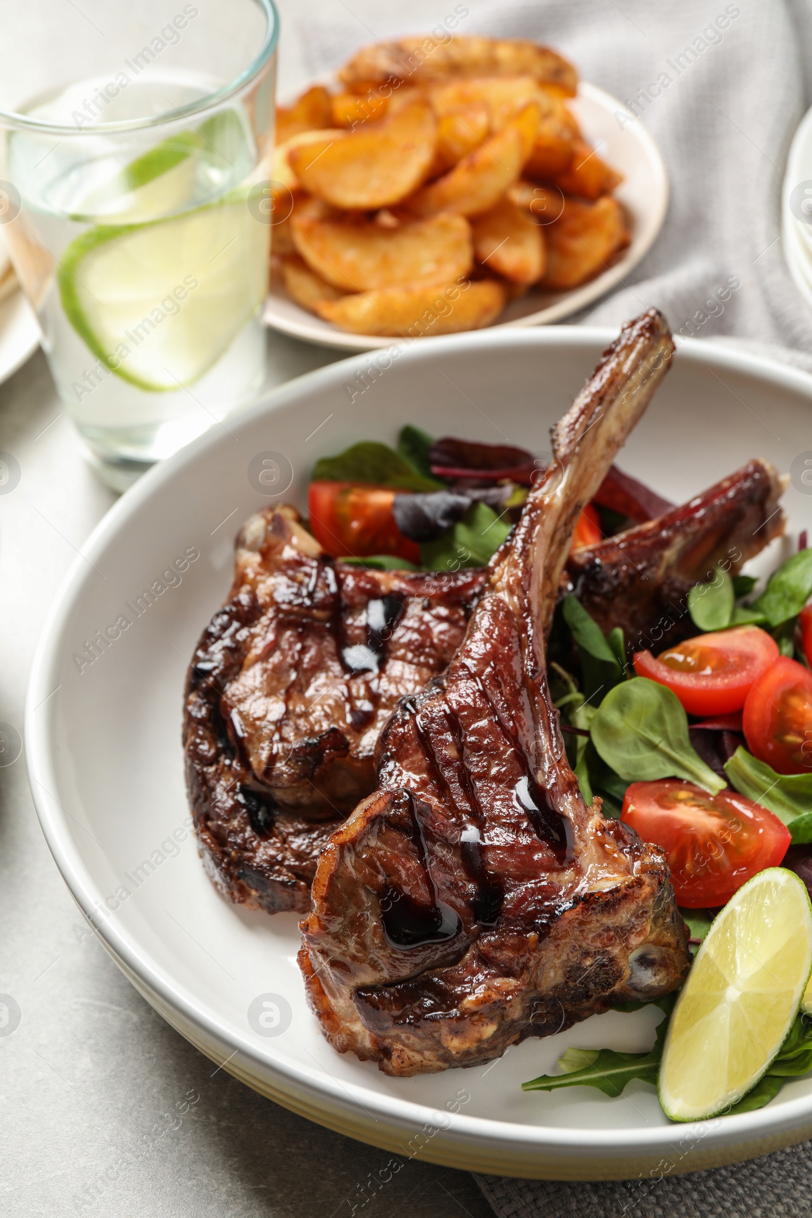 Photo of Delicious grilled ribs served on light grey table