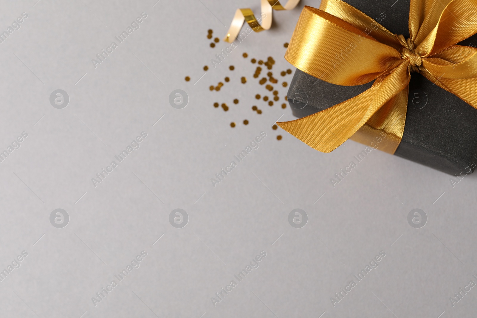 Photo of Beautifully wrapped gift box and confetti on grey background, flat lay. Space for text