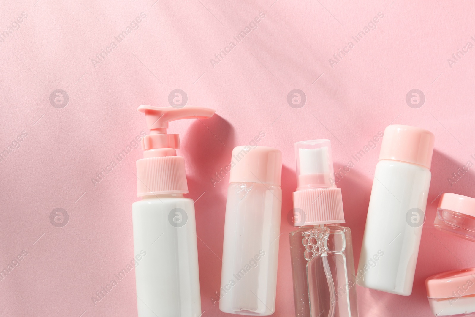 Photo of Cosmetic travel kit on pink background, top view. Space for text