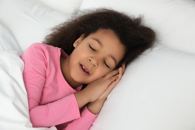 Cute little African-American girl sleeping in bed