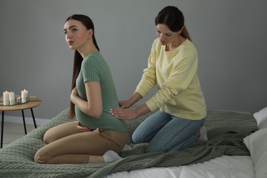 Doula massaging pregnant woman in bedroom. Preparation for child birth