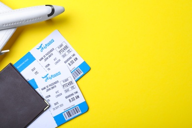 Photo of Toy airplane, passport and tickets on yellow background, flat lay with space for text. Travel agency concept