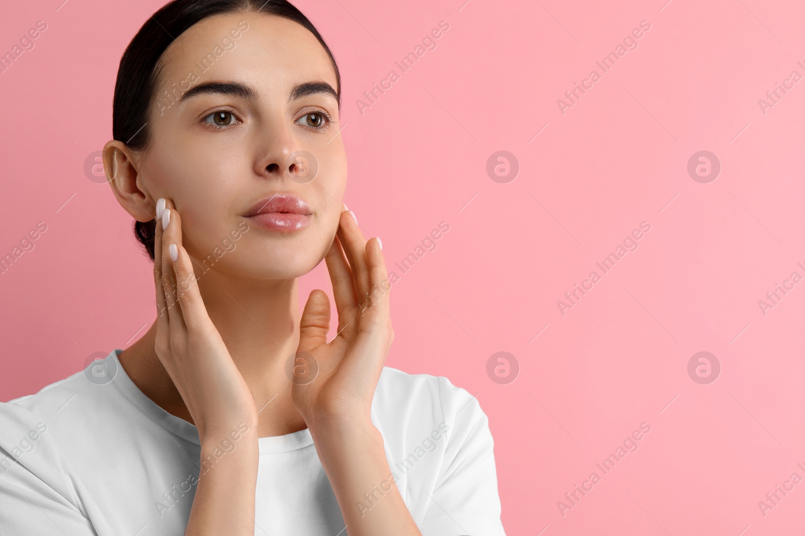 Photo of Woman with dry skin checking her face on pink background, space for text