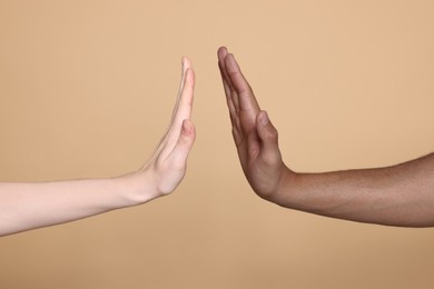 International relationships. People giving high five on light brown background, closeup