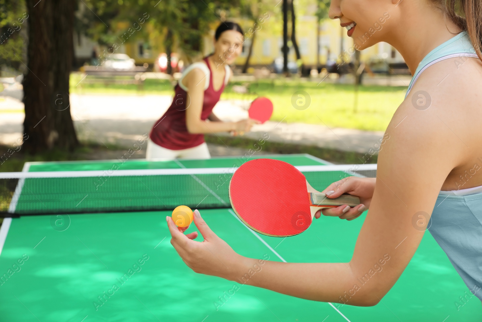 Photo of Young women playing ping pong in park, closeup