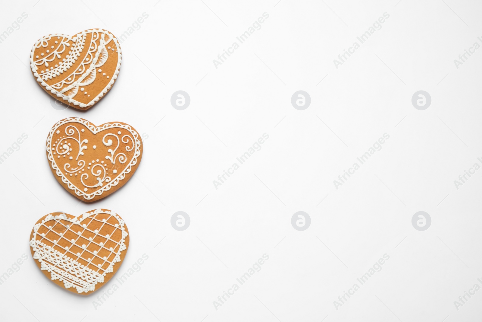 Photo of Gingerbread hearts decorated with icing on white background, flat lay. Space for text