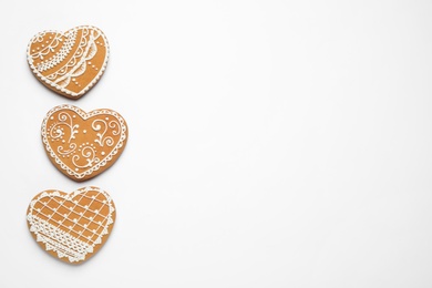 Gingerbread hearts decorated with icing on white background, flat lay. Space for text