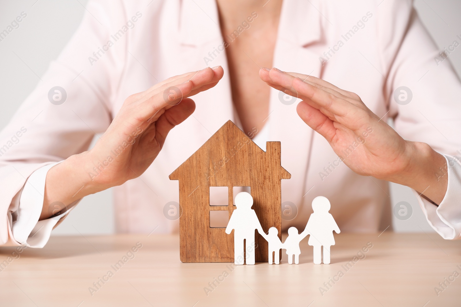 Photo of Female agent covering wooden house and family at table, closeup. Home insurance