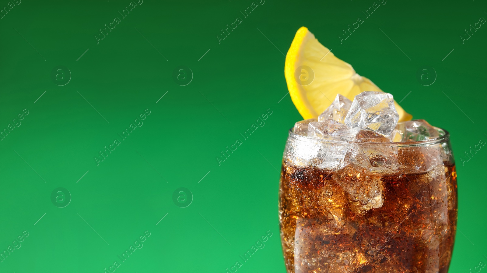 Image of Tasty refreshing soda drink with ice cubes and lemon slice on green background, closeup. Banner design with space for text