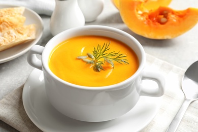 Delicious pumpkin cream soup in bowl on light table