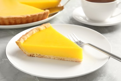 Photo of Slice of delicious homemade lemon pie on grey table